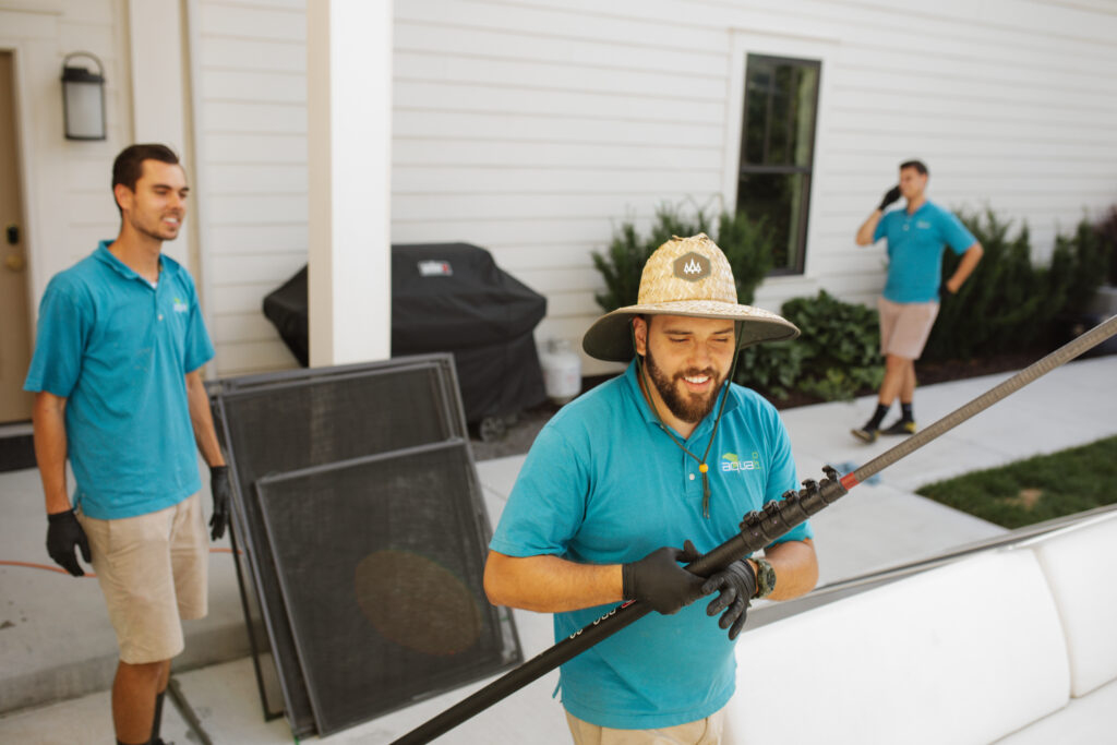 AquaPro exterior cleaning crew preparing for a job with tools and window screens at a residential property in Utah